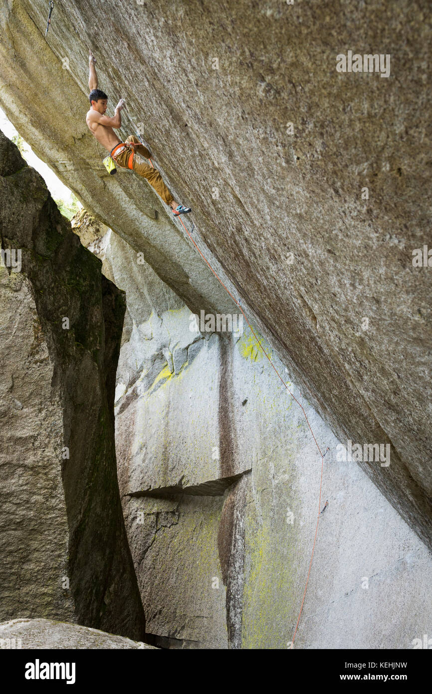 Mixed race boy climbing rock Stock Photo