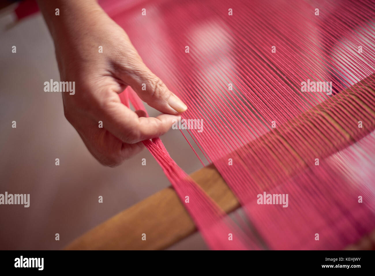 Hand of Hispanic woman weaving fabric on loom Stock Photo