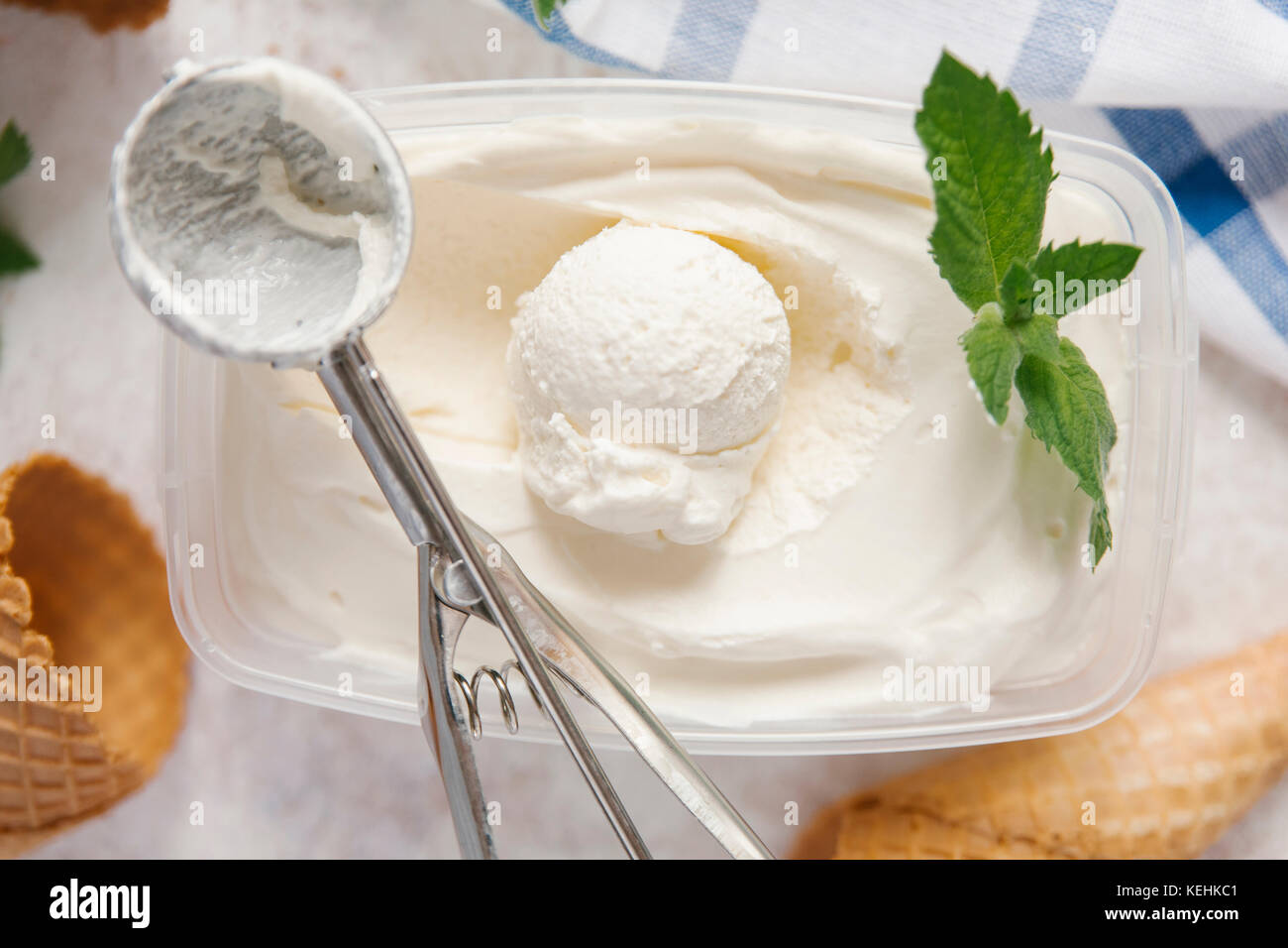 Scoop of ice cream in container with mint near cones Stock Photo Alamy