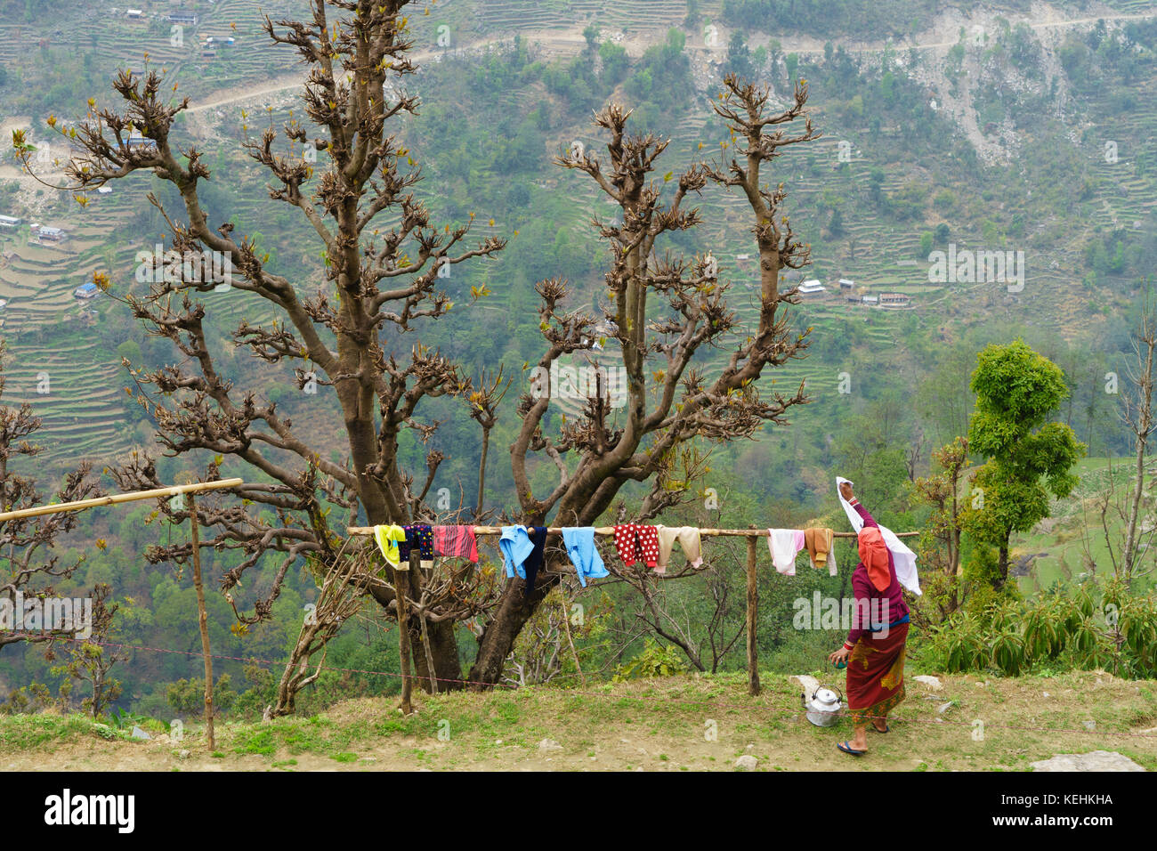Nepalese woman hanging laundry on a wooden pole. Stock Photo
