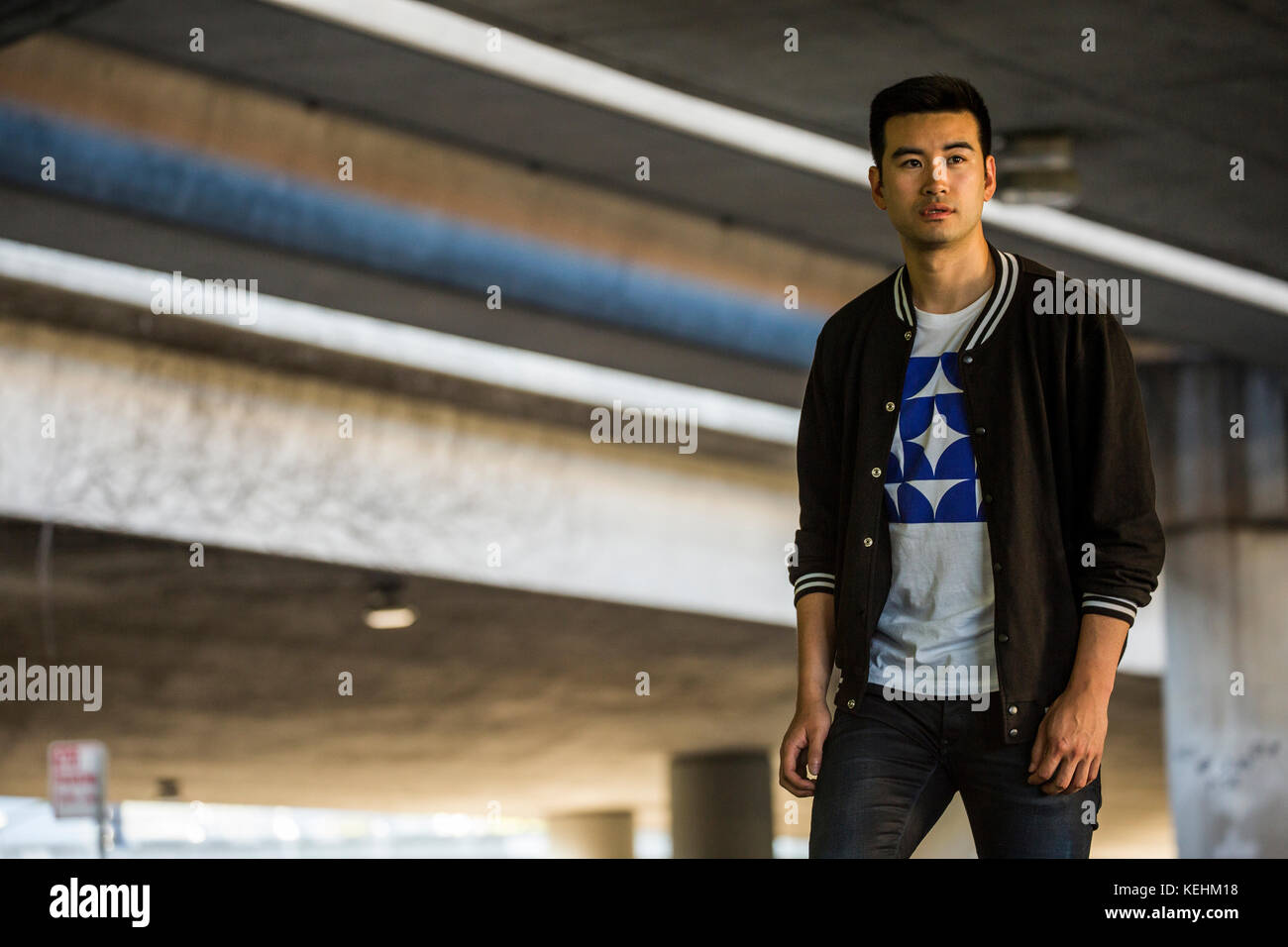 Chinese man standing under urban overpass Stock Photo