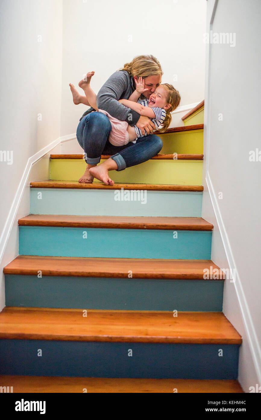 Caucasian mother kissing daughter on staircase Stock Photo