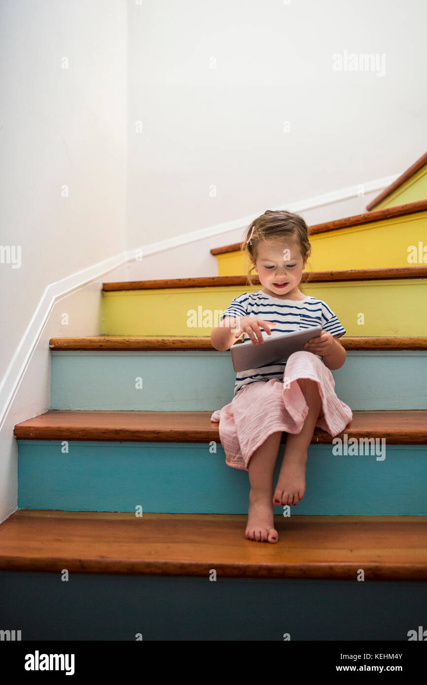 Caucasian girl using digital tablet on staircase Stock Photo