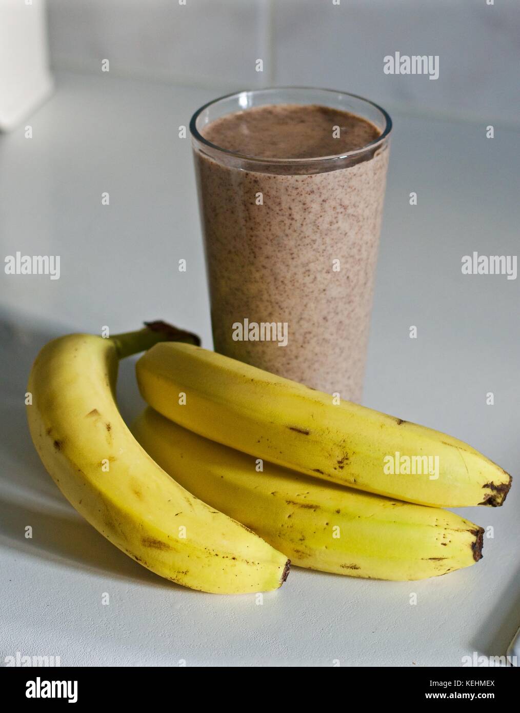 Banana and chocolate smoothie on kitchen counter with three bananas ...