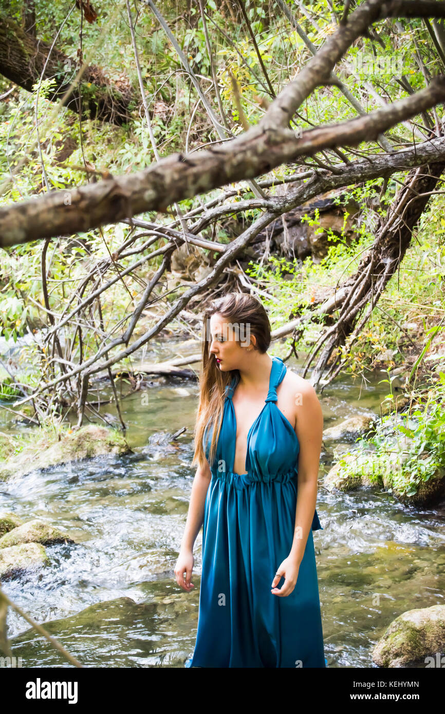 Beautiful woman on the bank of a mountain river with an evening dress ...