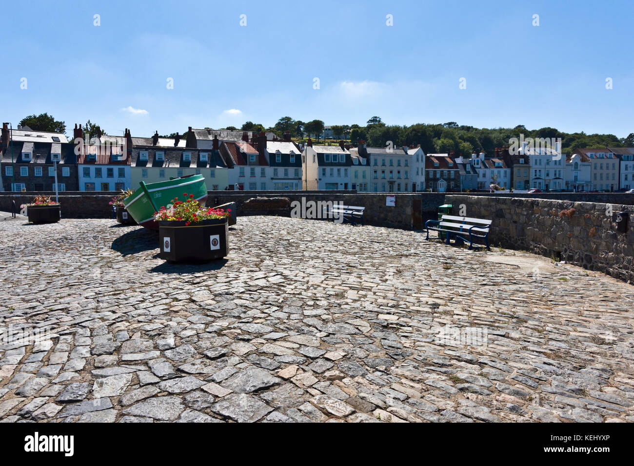 Remains of old coastal fort north of St Peter Port with a display of flower pots and seating with view across Little Russell channel Stock Photo