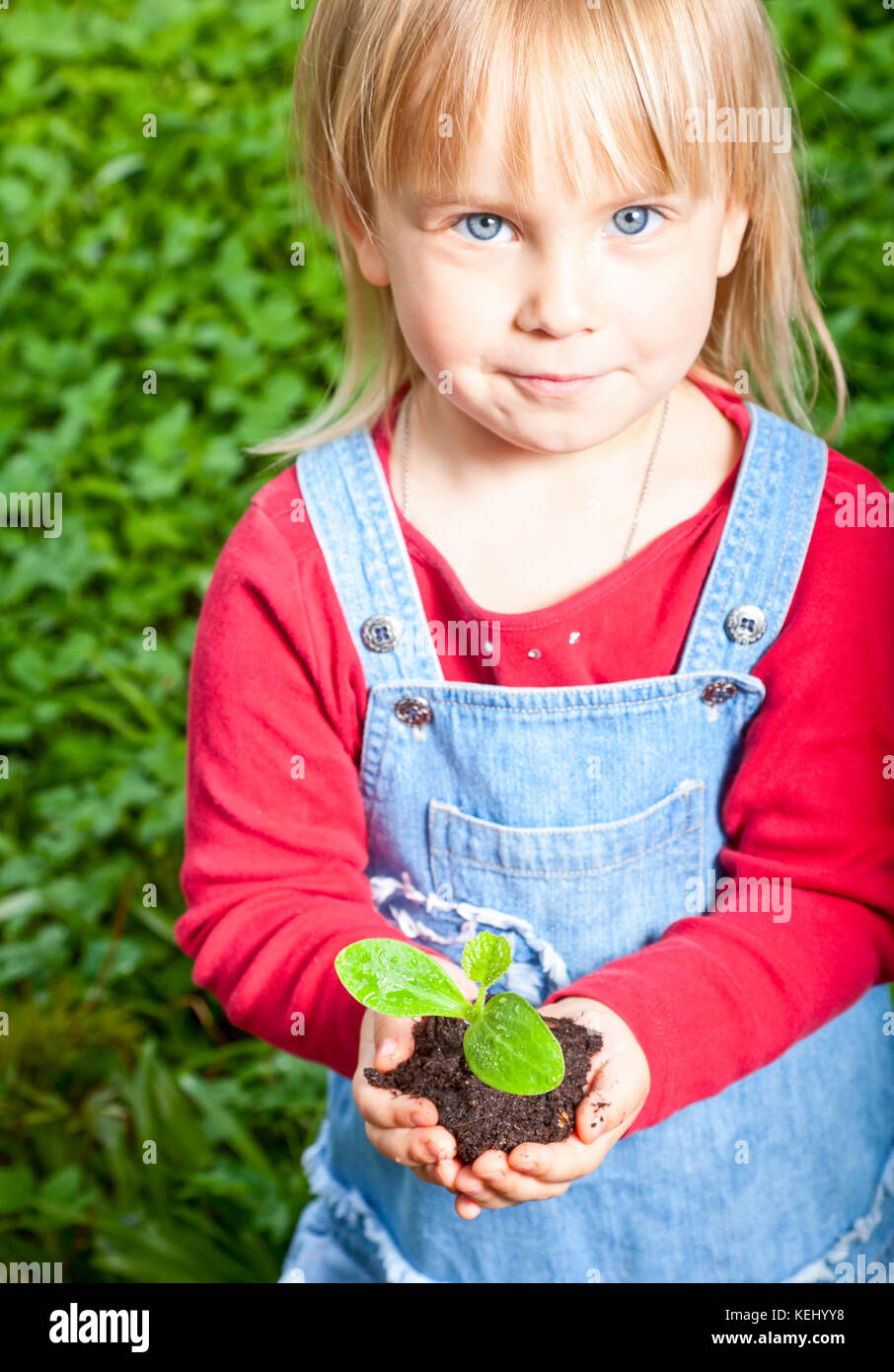 Blonde girl showing seeding with ground, focus on sprout Stock Photo