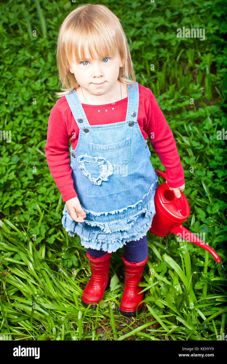 Little girl holding red watering can Stock Photo