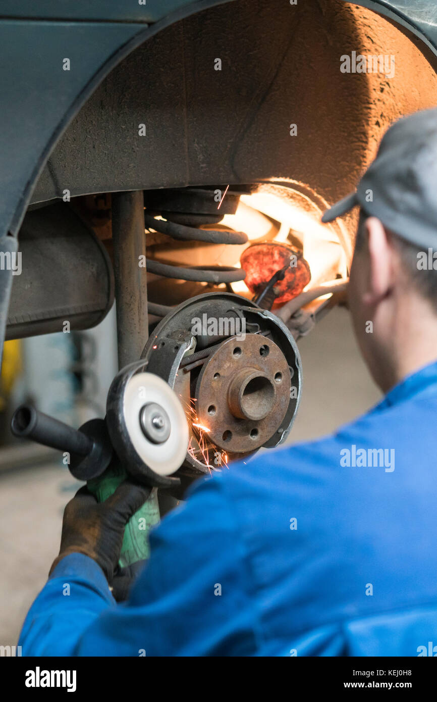 car mechanic worker replacing brakes of lifted automobile at auto
