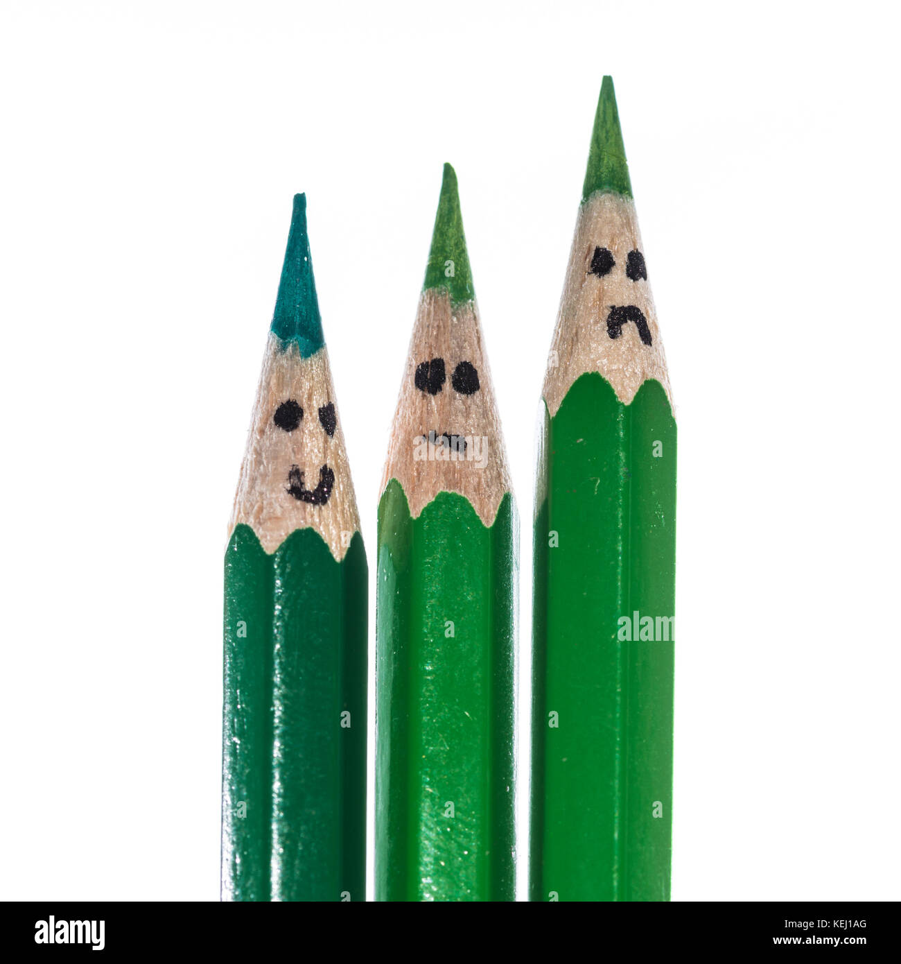 A macro shot of a trio of green coloured pencils with faces drawn on