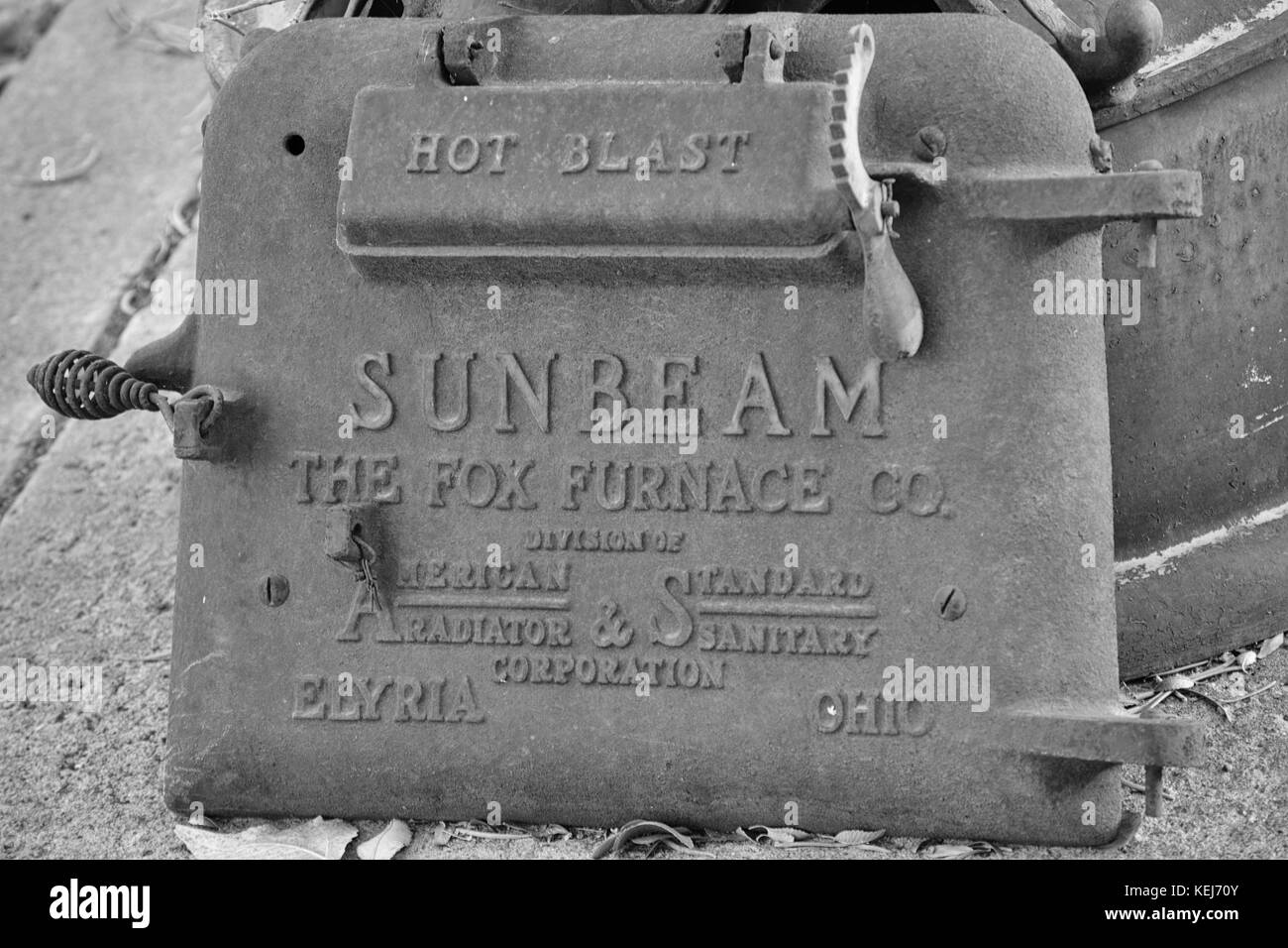 Old cast iron furnace door used as a decoratiion alongside a mailbox base  on a city sidewalk Stock Photo - Alamy
