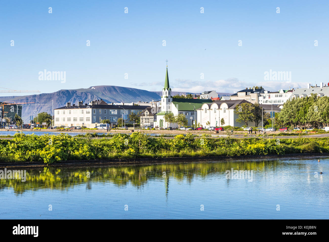 Reykjavik cityscape viewed from across the Tjornin lake in the heart of Iceland capital city on a sunny summer day. Stock Photo