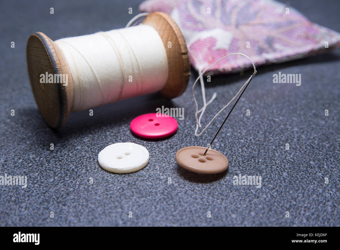 Needle in the button with old thread Stock Photo - Alamy