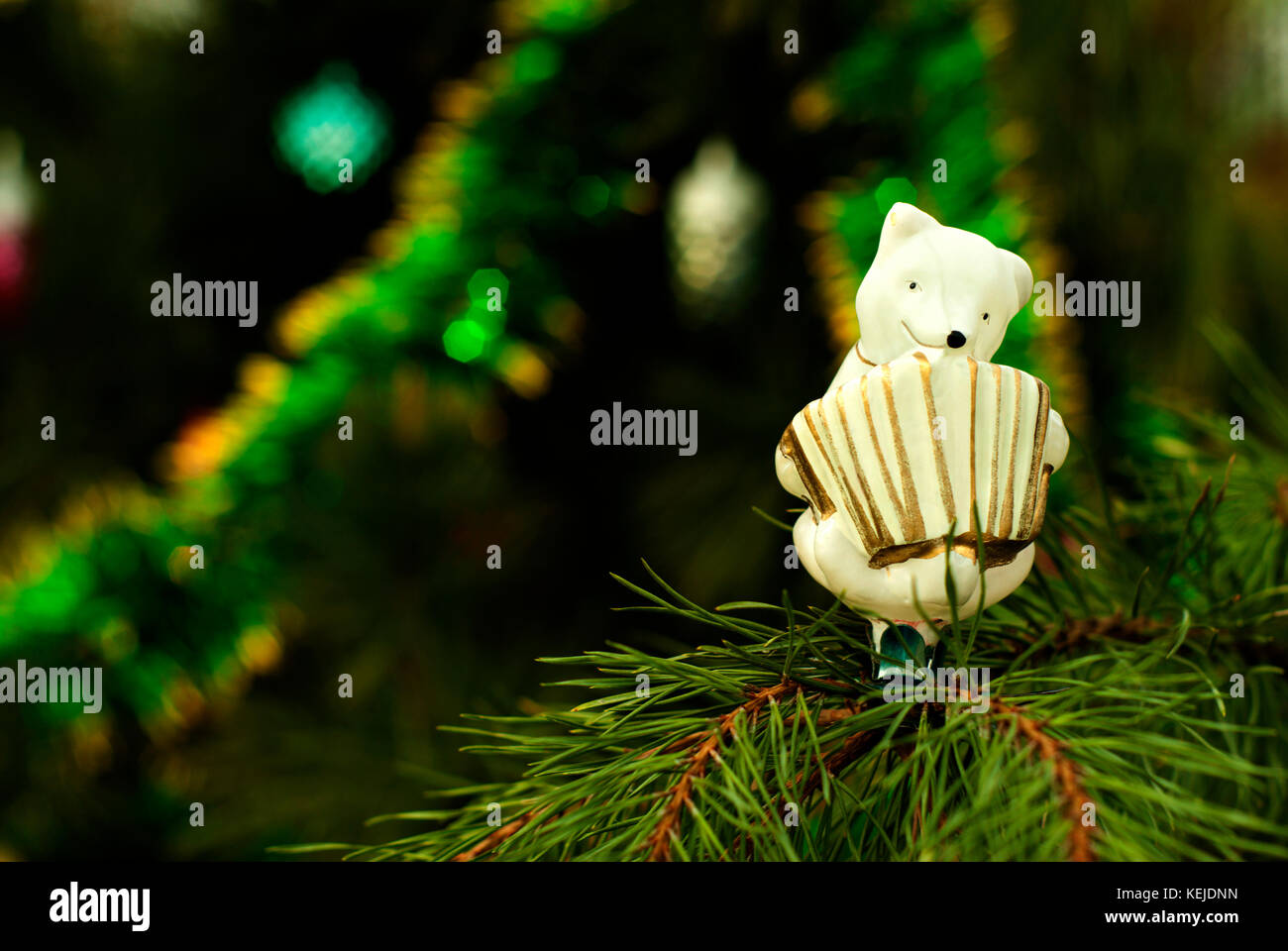retro, glass, hand painted Christmas ornament - white bear-accordionist- on a background of a blurred Christmas tree Stock Photo