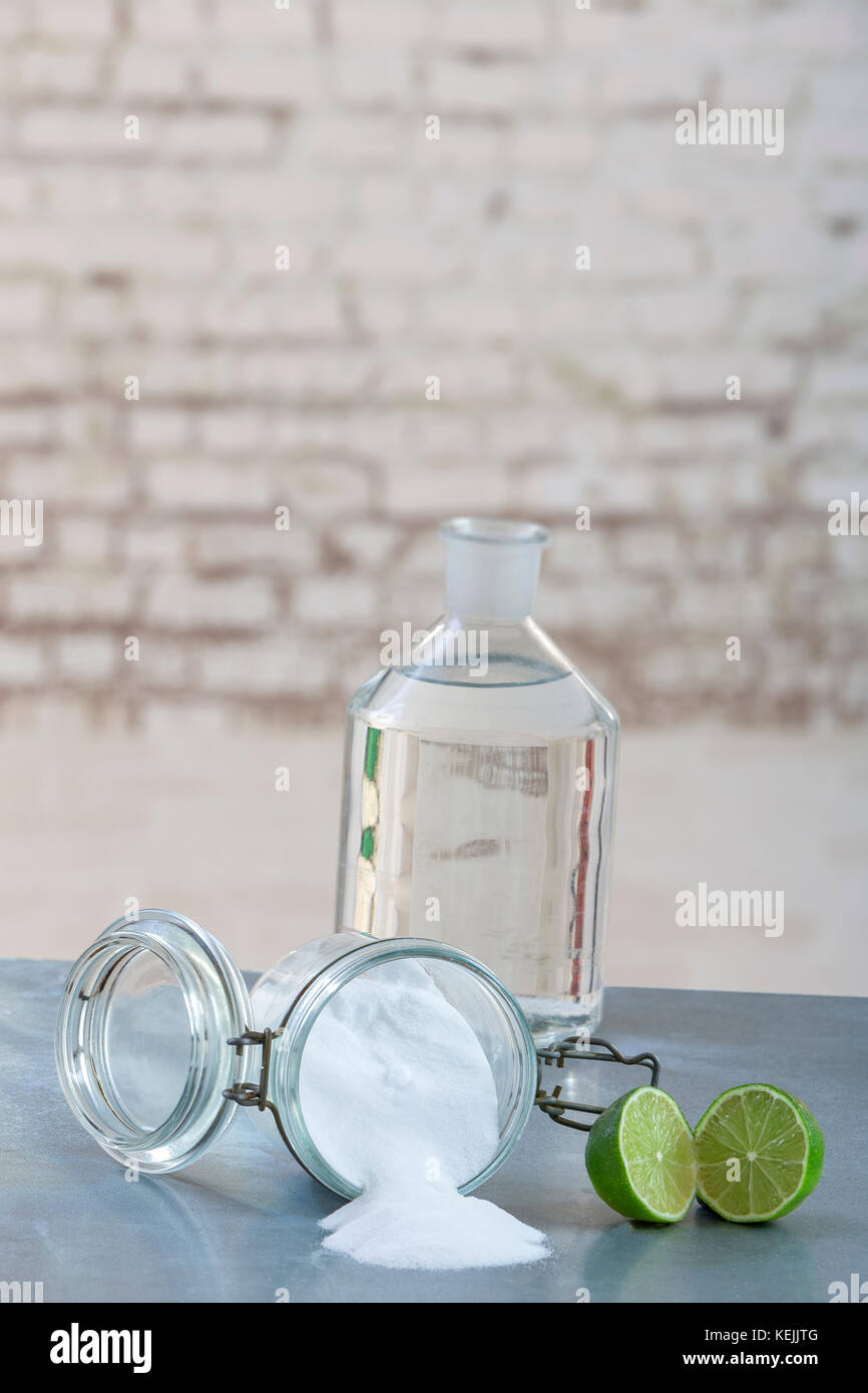 Natural cleaning products, including sodium bicarbonate, invert jar, baking soda, lemon, vinegar,on grey table on old grey wall Stock Photo