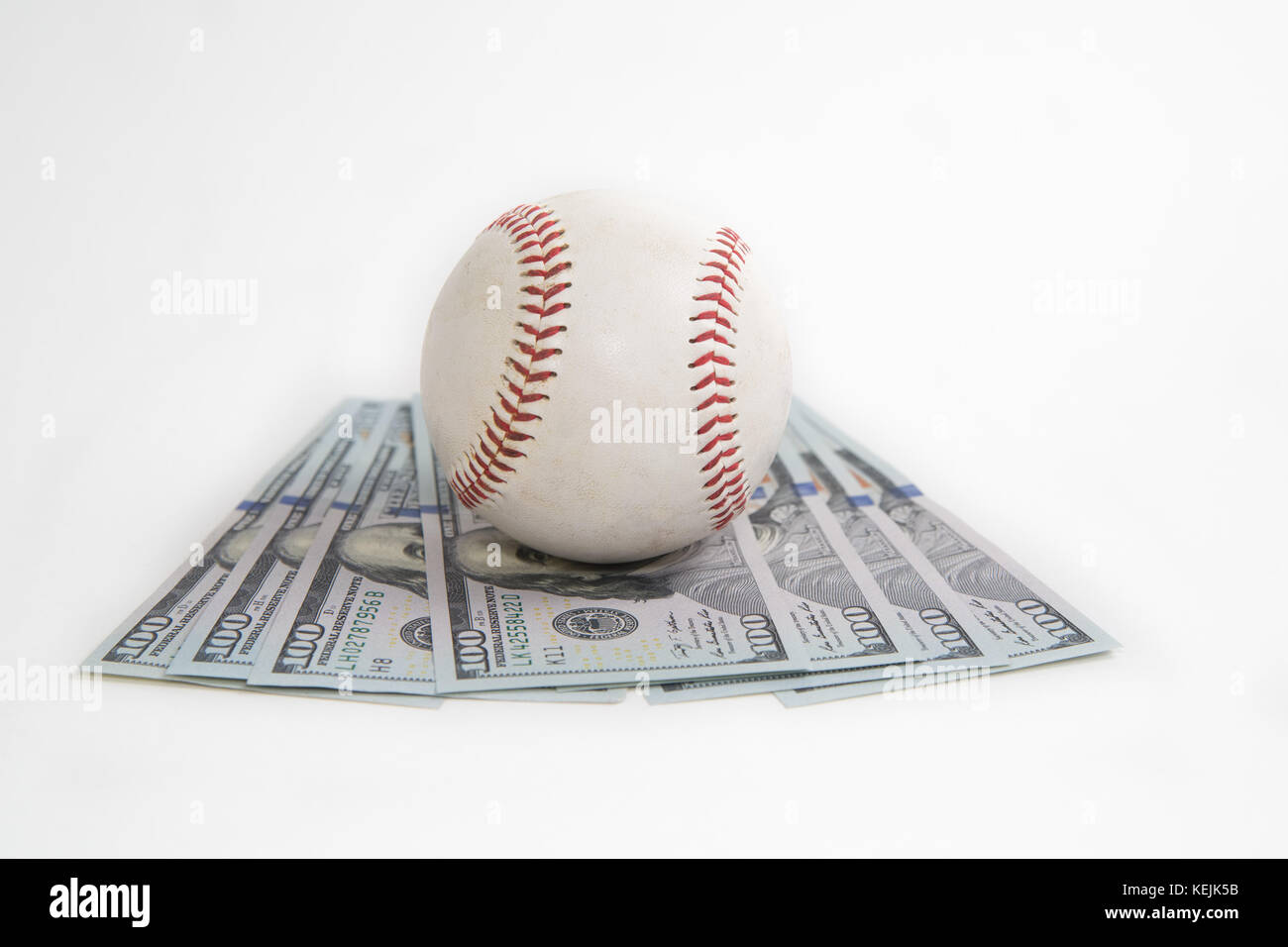 Baseball sits atop hundred dollar bills to represent the cost of sports Stock Photo Alamy