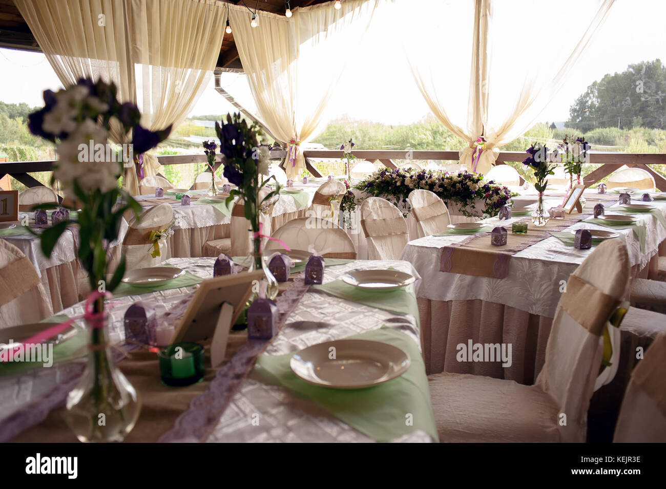 Beautifully decorated table for the wedding ceremony. Served banquet table decorated with fresh flowers in the open air. Stock Photo
