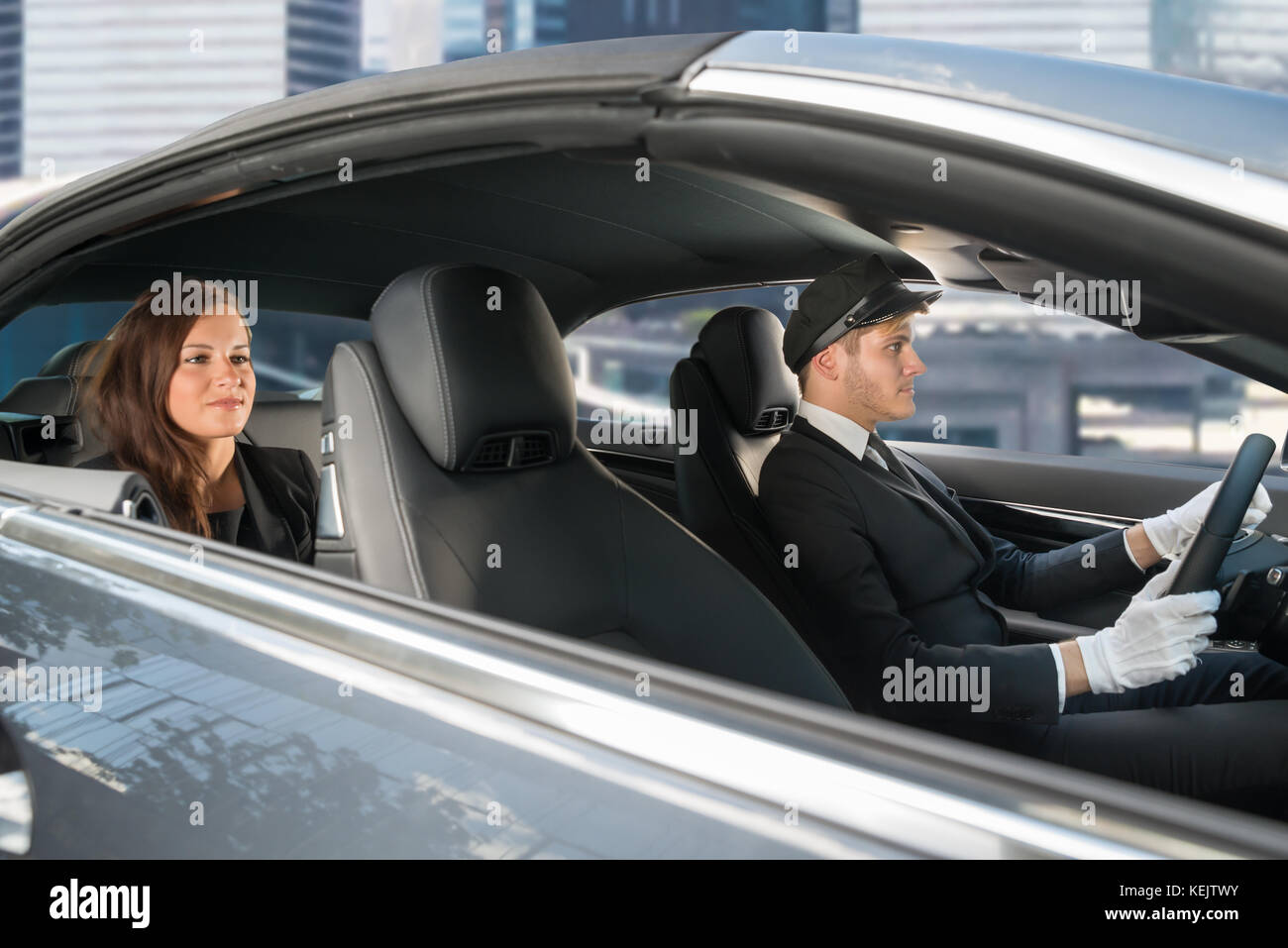 Beautiful Young Woman Traveling In A Car With Male Handsome Chauffeur Stock Photo