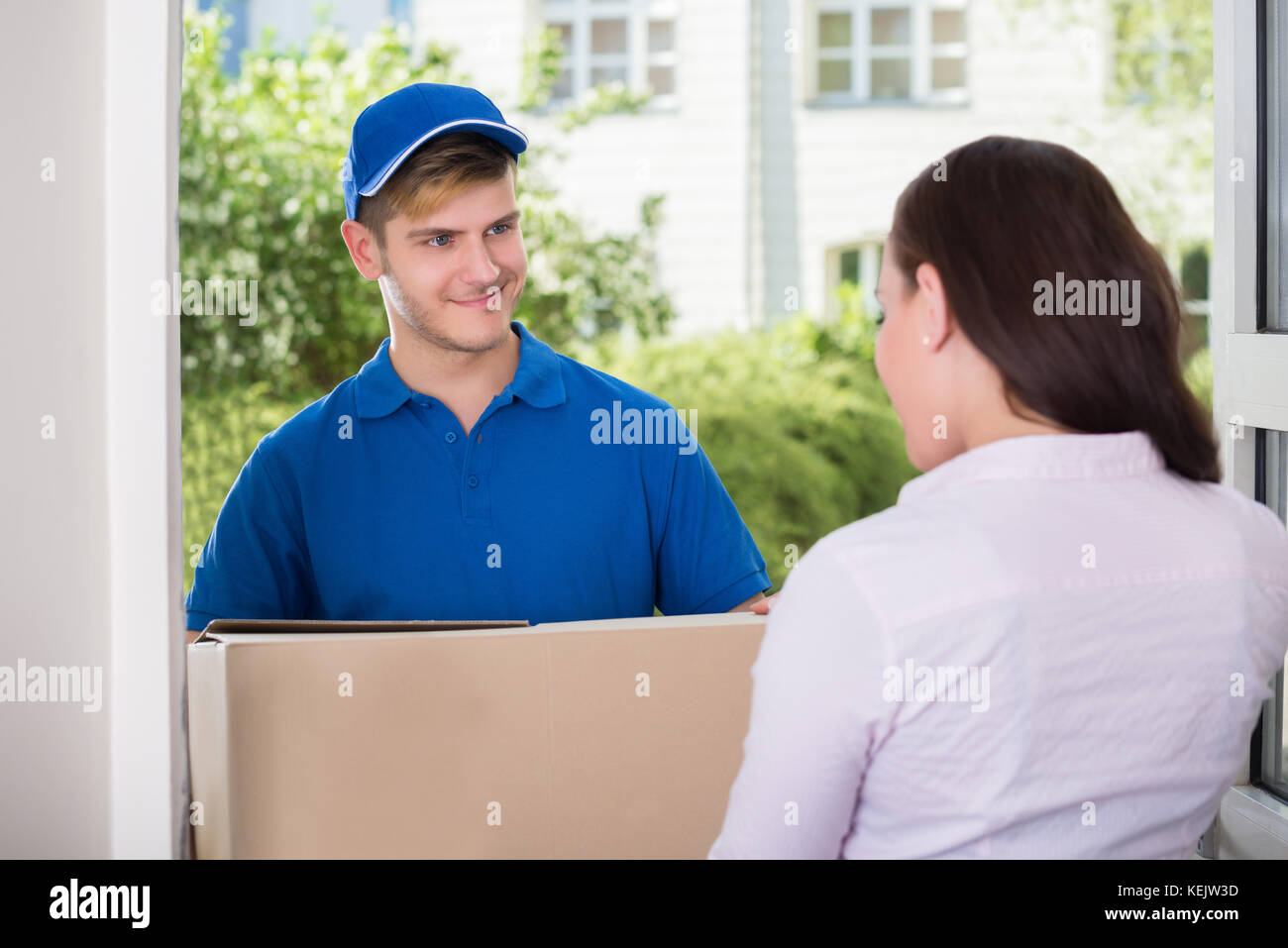 Woman Receiving Package From Happy Delivery Man Stock Photo