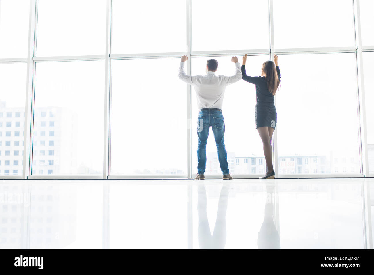 Business man and business woman rised hands in office team satisfied with result, won profitable contract, group of winners celebrate victory or great Stock Photo