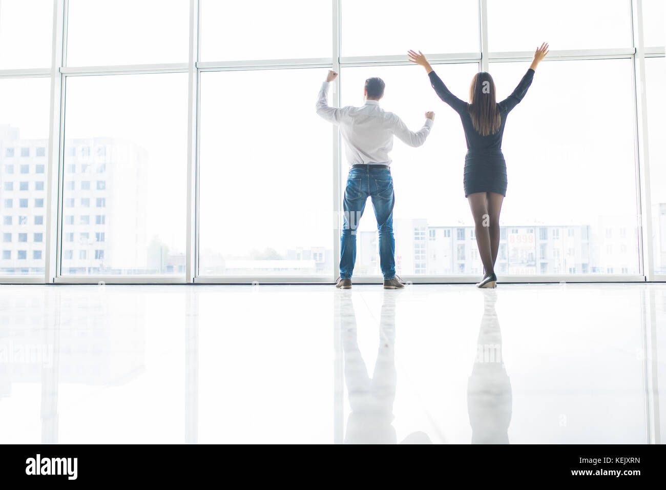 Business man and business woman rised hands in office team satisfied with result, won profitable contract, group of winners celebrate victory or great Stock Photo