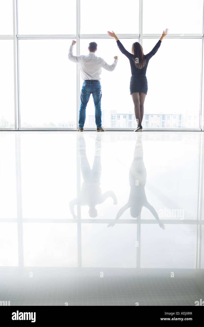 Business man and business woman rised hands in office team satisfied with result, won profitable contract, group of winners celebrate victory or great Stock Photo