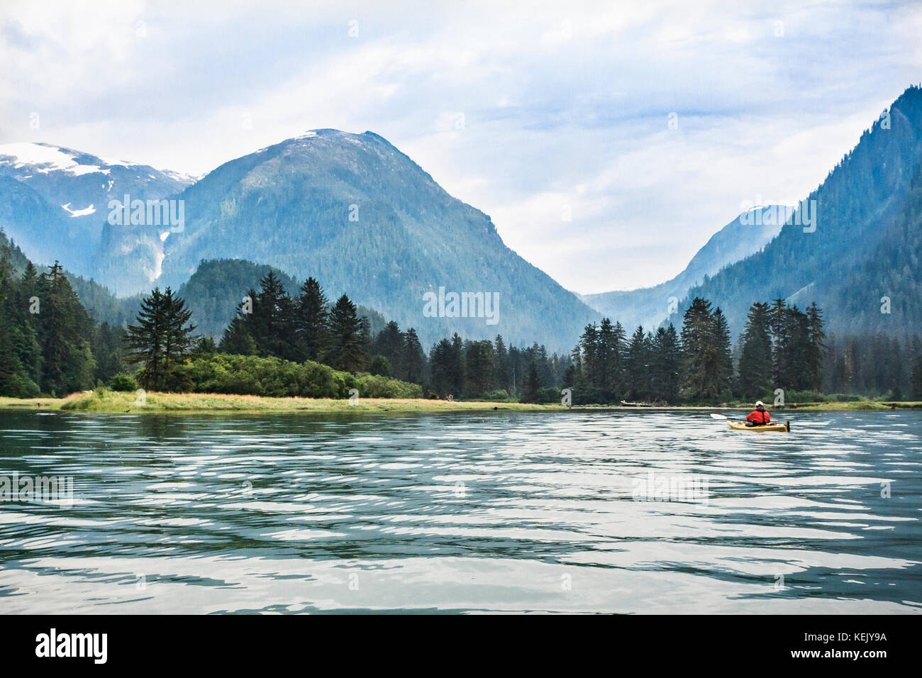 A lone kayaker approaches the river mouth at the head of remote Khutze Inlet, a conservancy area in the Great Bear Rainforest on BC's Inside Passage. Stock Photo