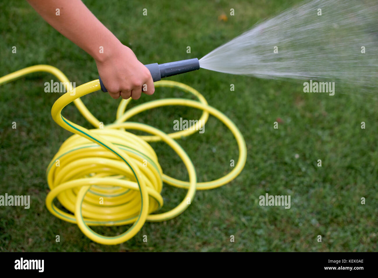 Yellow plastic hose pipe with sprayer at the end Stock Photo