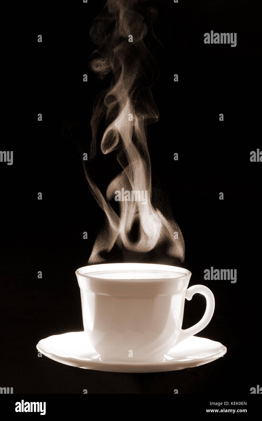White cup coffee with steam consisted of little water  drops on a dark black background. Stock Photo