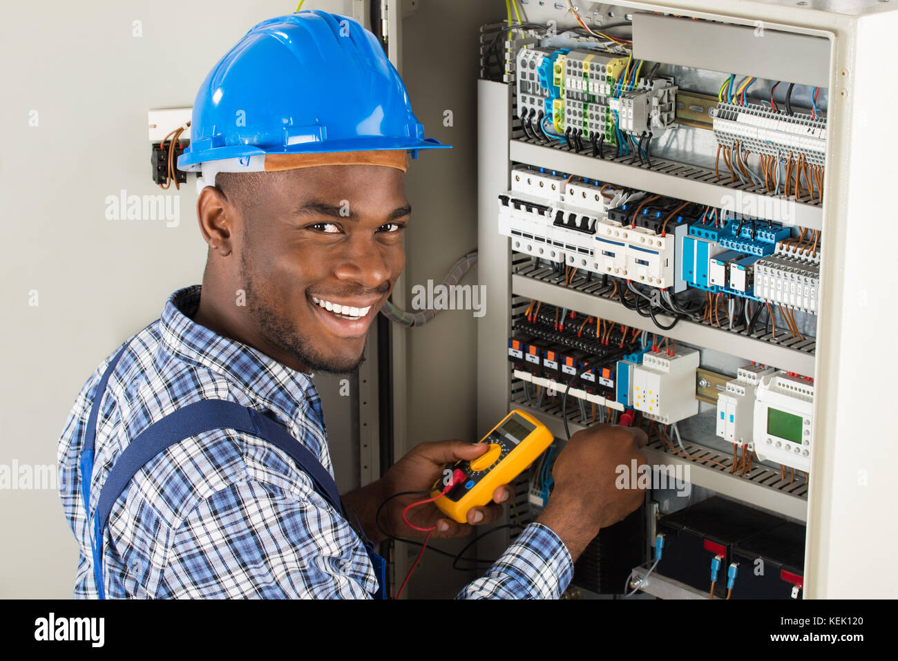 Young African Male Technician Examining Fusebox With Multimeter Probe Stock Photo