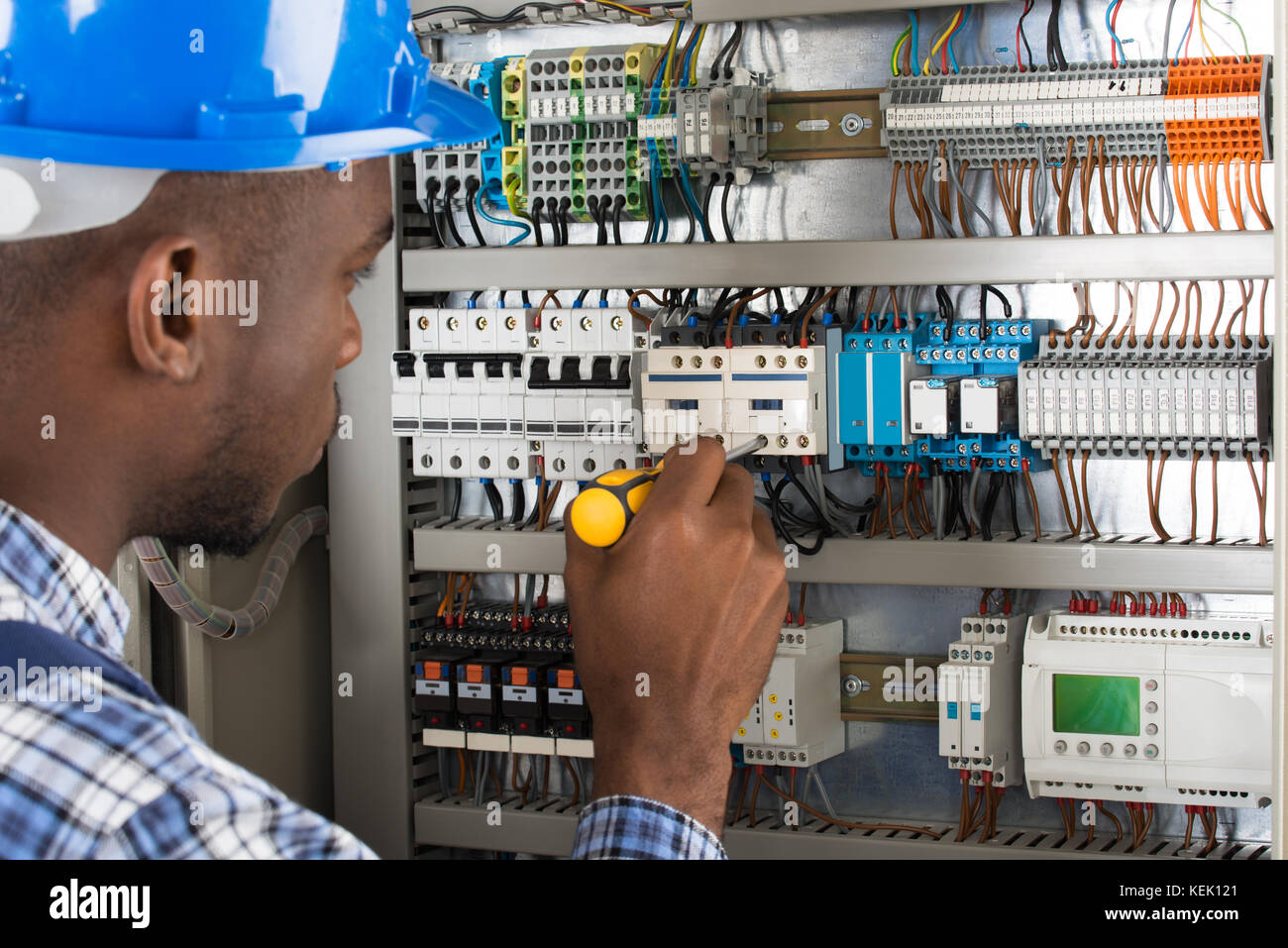 Close-up Of Young Male Technician Examining Fusebox With Screwdriver Stock Photo