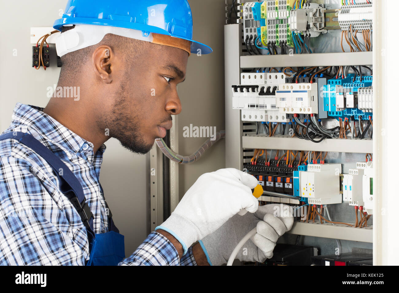 Young African Male Technician Repairing Fusebox With Screwdriver Stock Photo