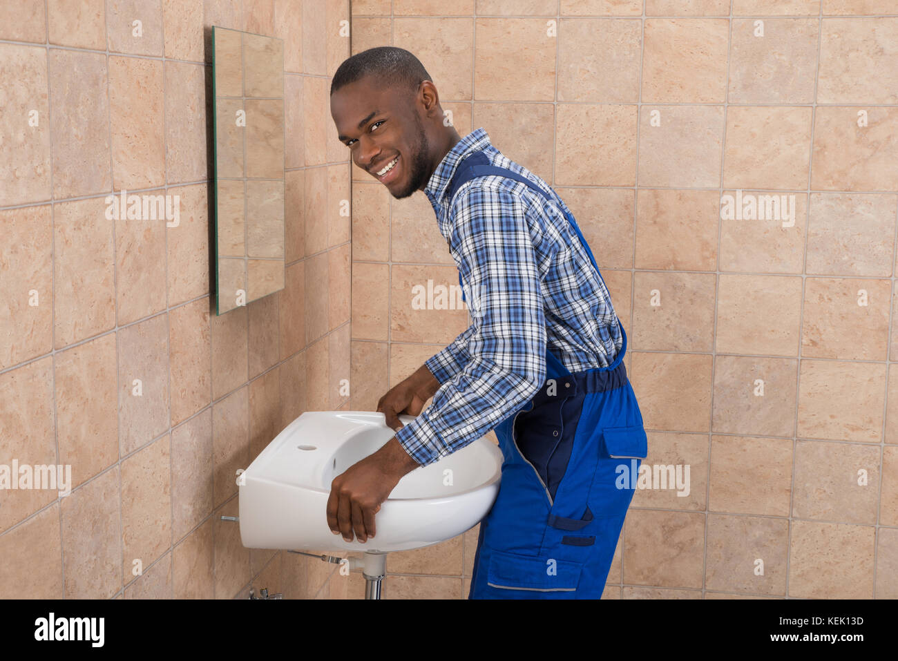 Side View Of Young African Male Plumber Fixing Sink In Bathroom Stock Photo  - Alamy