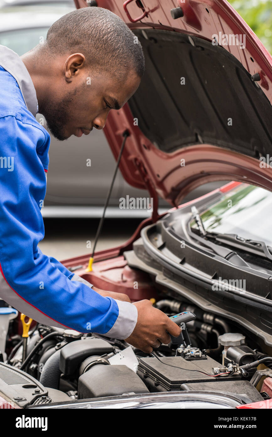 Close-up Of Male Mechanic Checking Car Battery Level With Multimeter Stock Photo