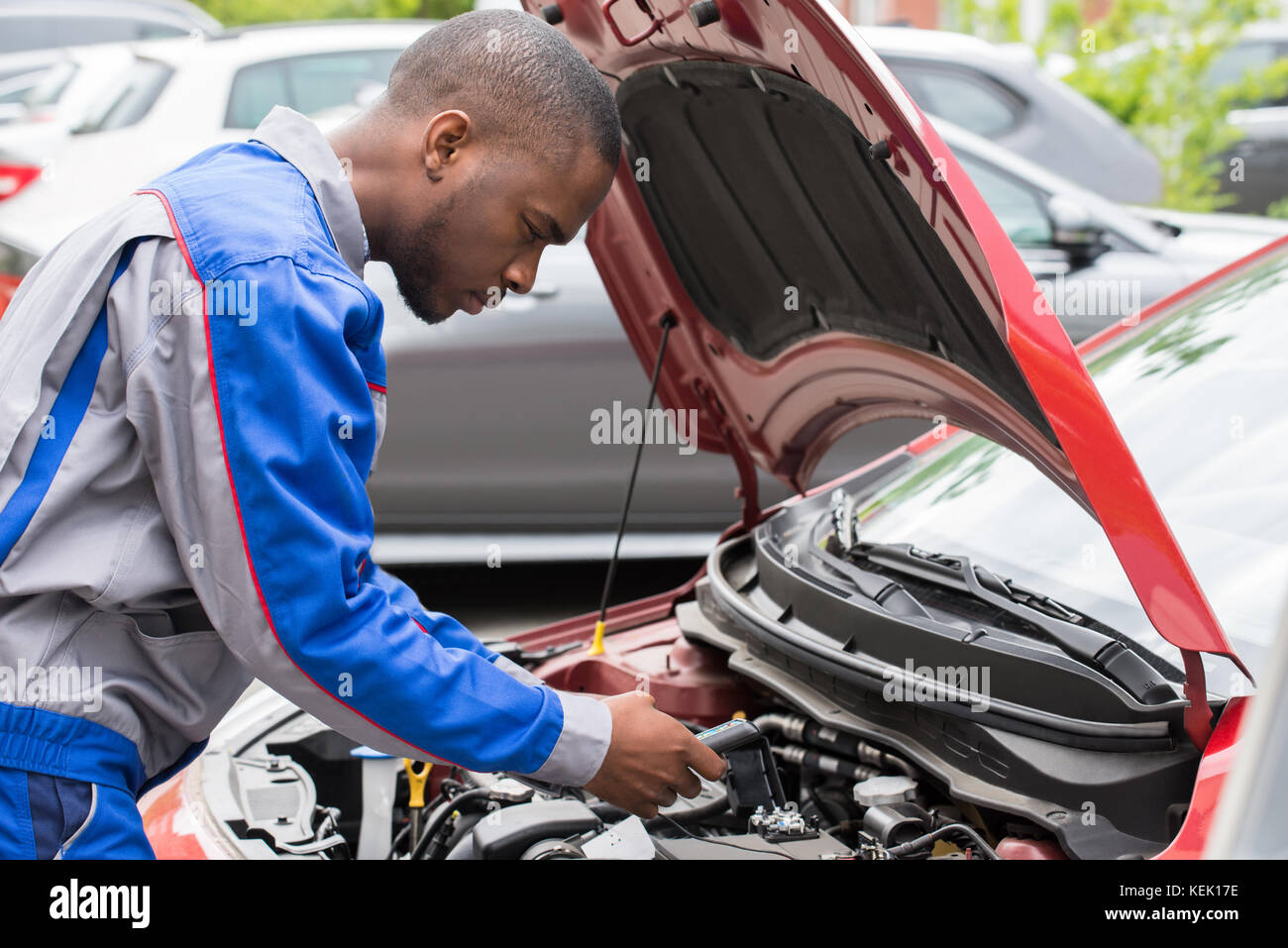 Close-up Of Male Mechanic Checking Car Battery Level With Multimeter Stock Photo