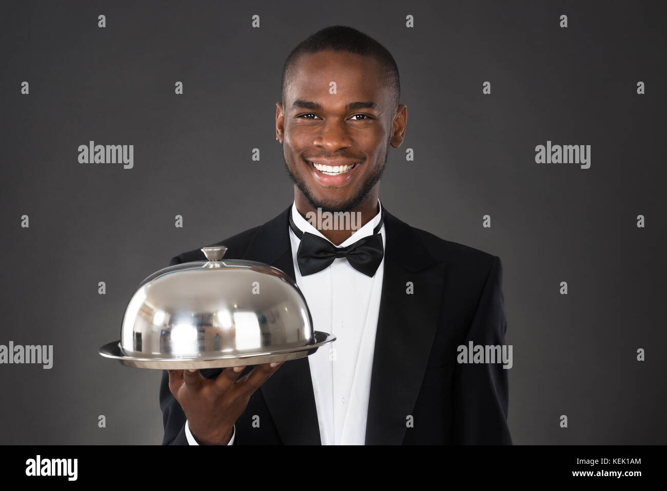Portrait Of Happy Waiter Serving Meal In Cloche Stock Photo