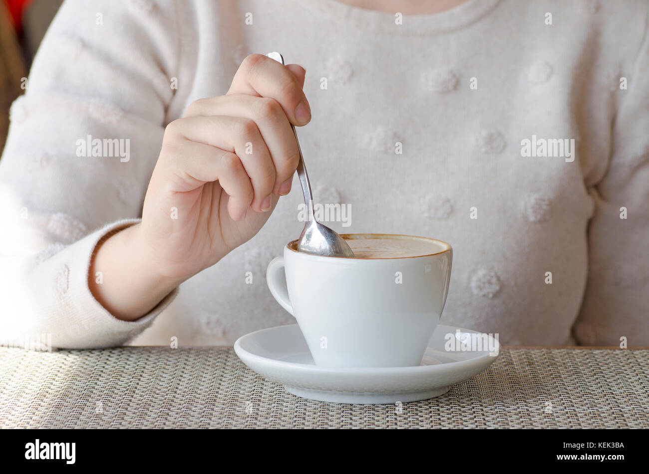 Closeup photo of a woman drinking coffee from a white porcelain cup and