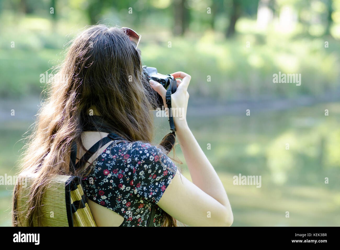 A rear view of a young woman with sunglasses and a backpack