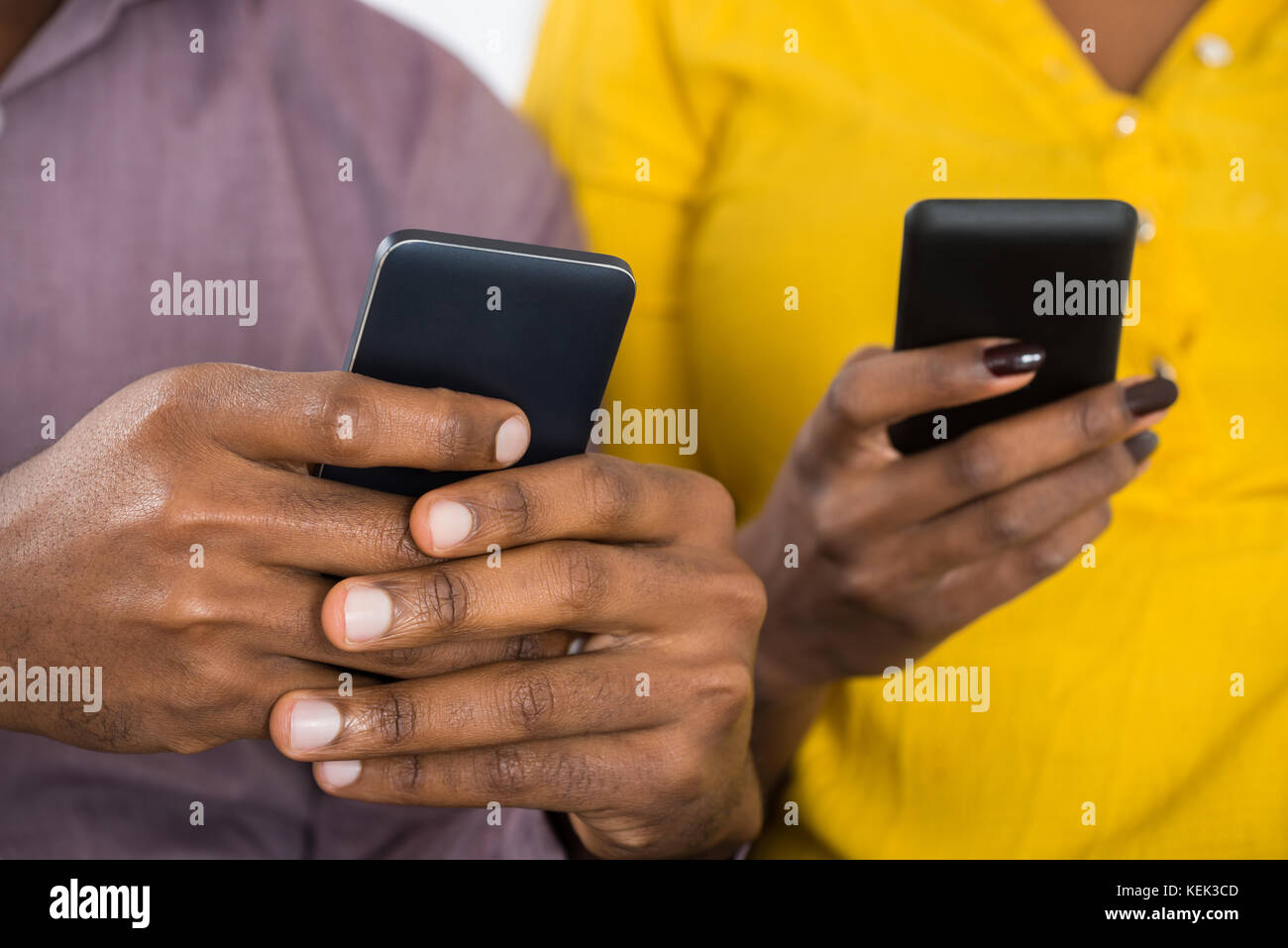 Close-up Of African Couple Holding Mobile Phones In Hand Stock Photo