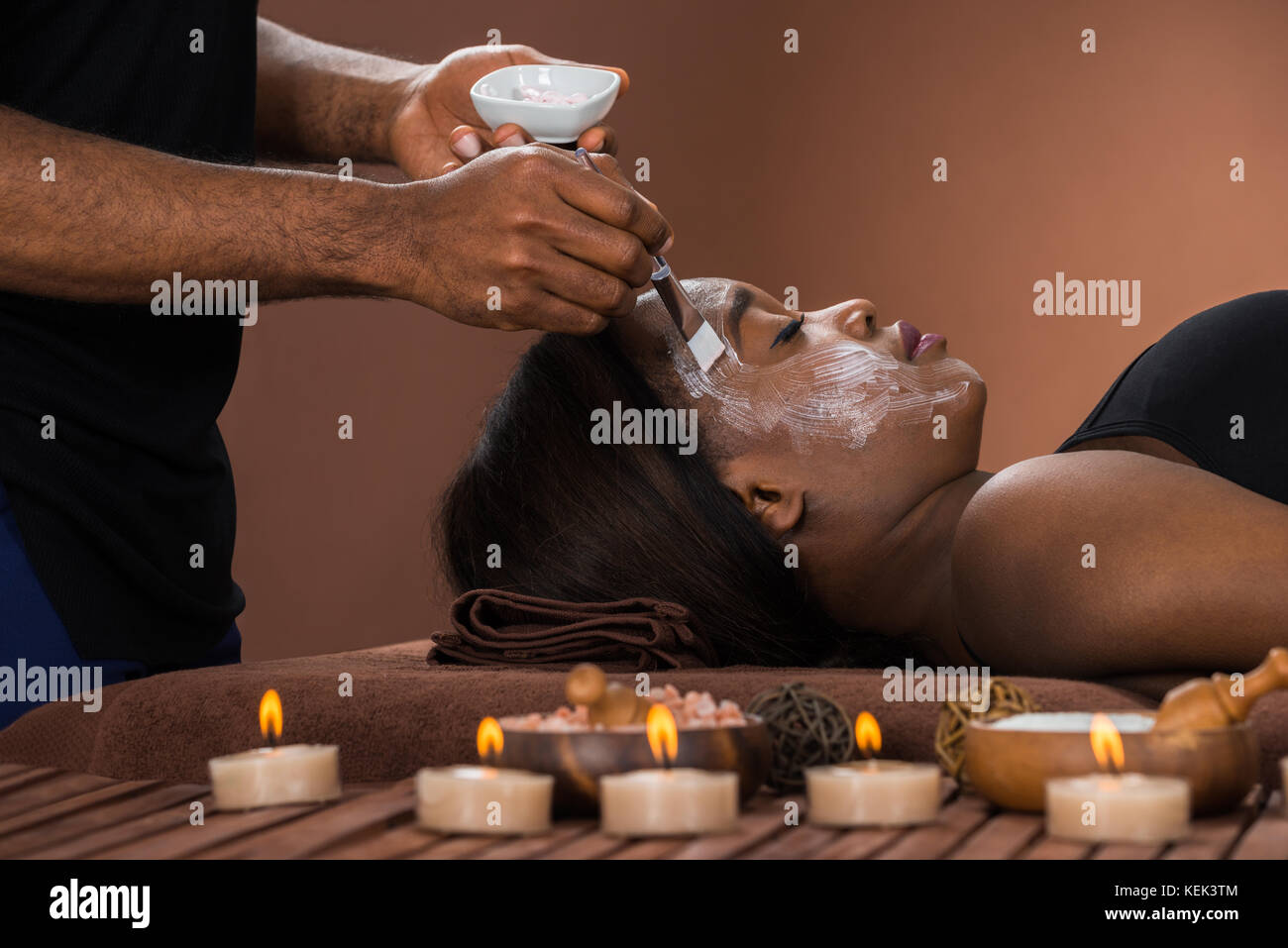 Young African Woman Getting Facial Mask At Spa Stock Photo