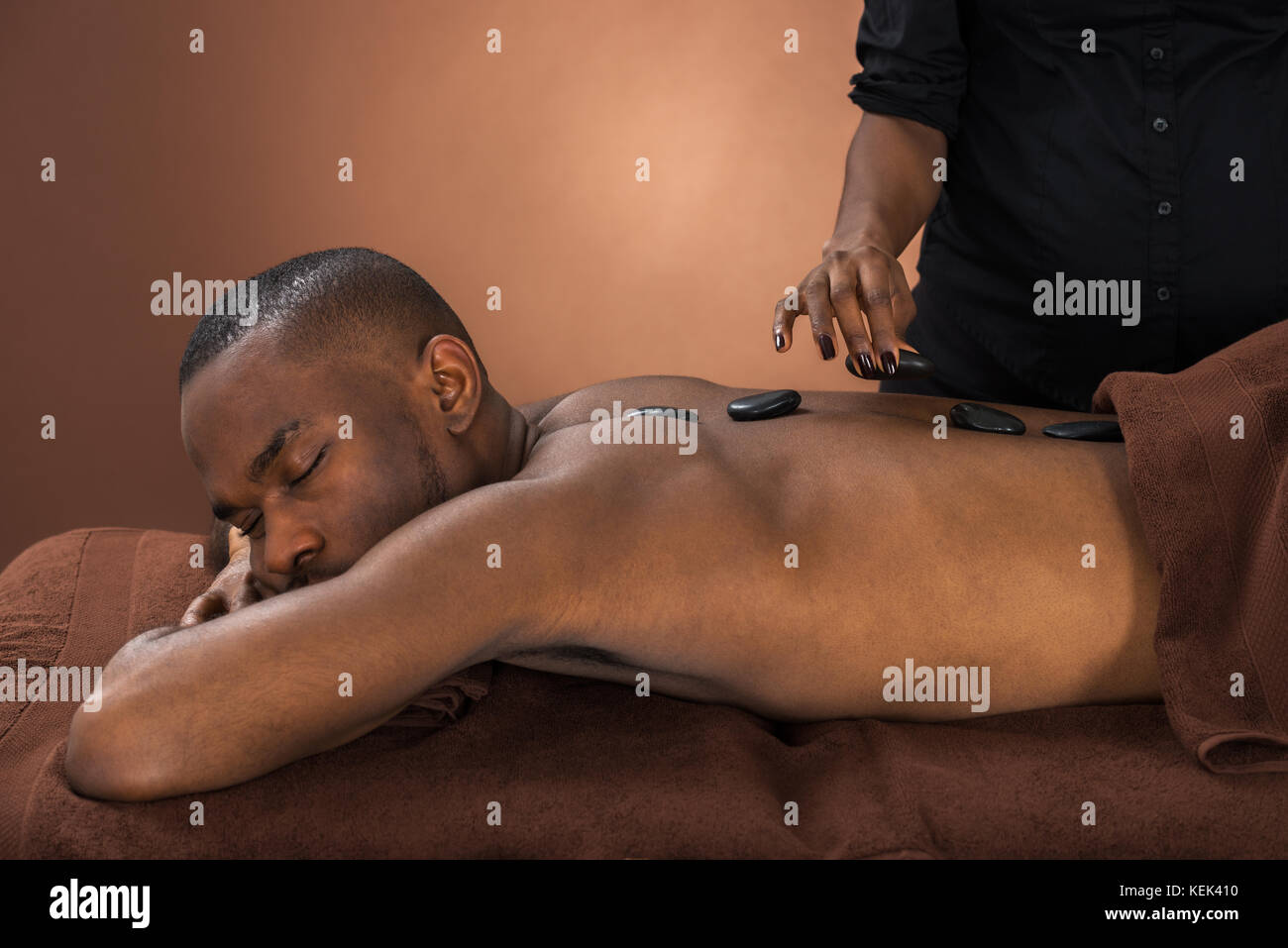 African Man Relaxing In A Spa Getting Hot Stone Therapy Stock Photo