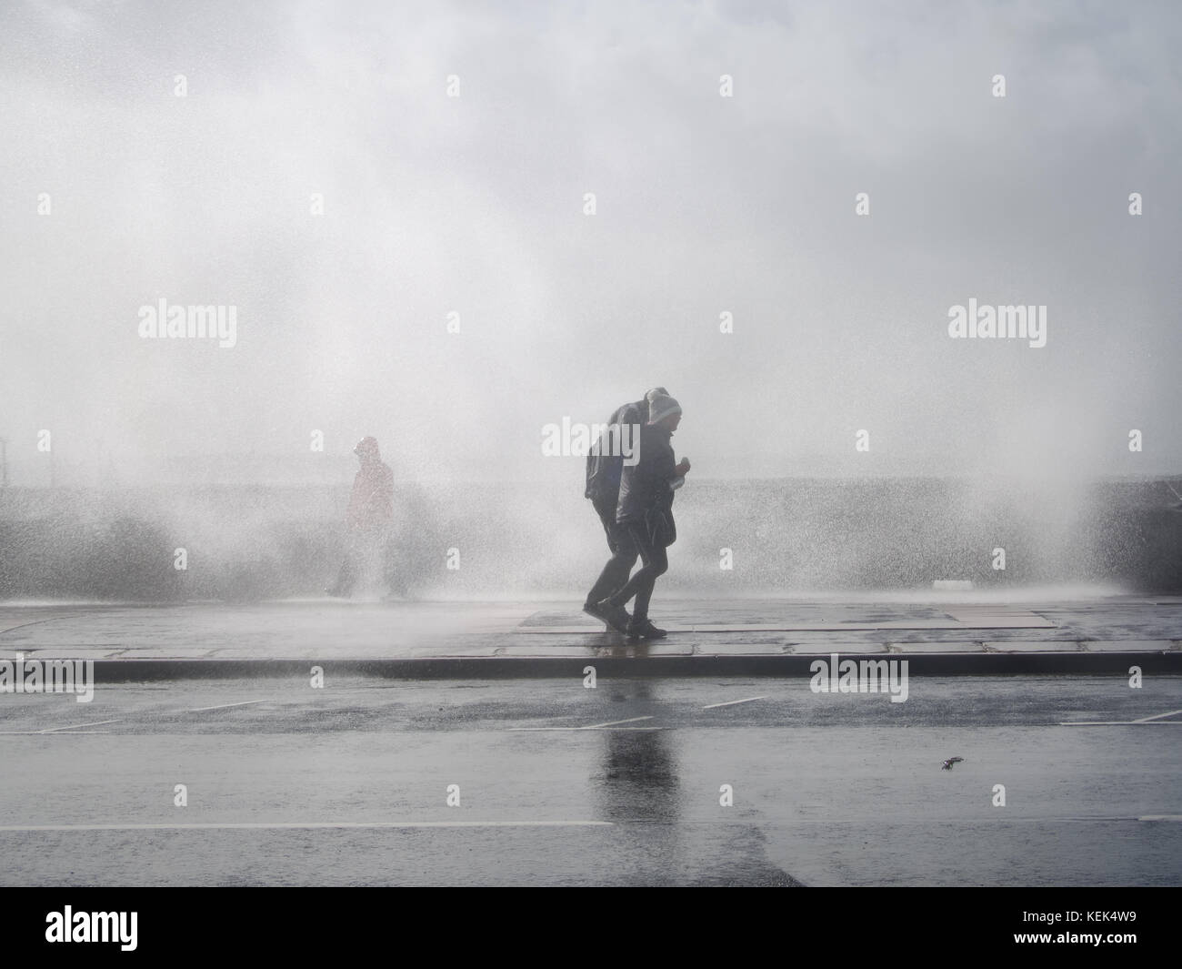 Southsea, Portsmouth, UK. 21st Oct, 2017. UK Weather. A couple walking along Southsea promenade ar hit by large waves breaking over the sea wall of Southsea seafront as Storm Brian hits the Southern coastline of the UK at high tide. Credit: simon evans/Alamy Live News Stock Photo