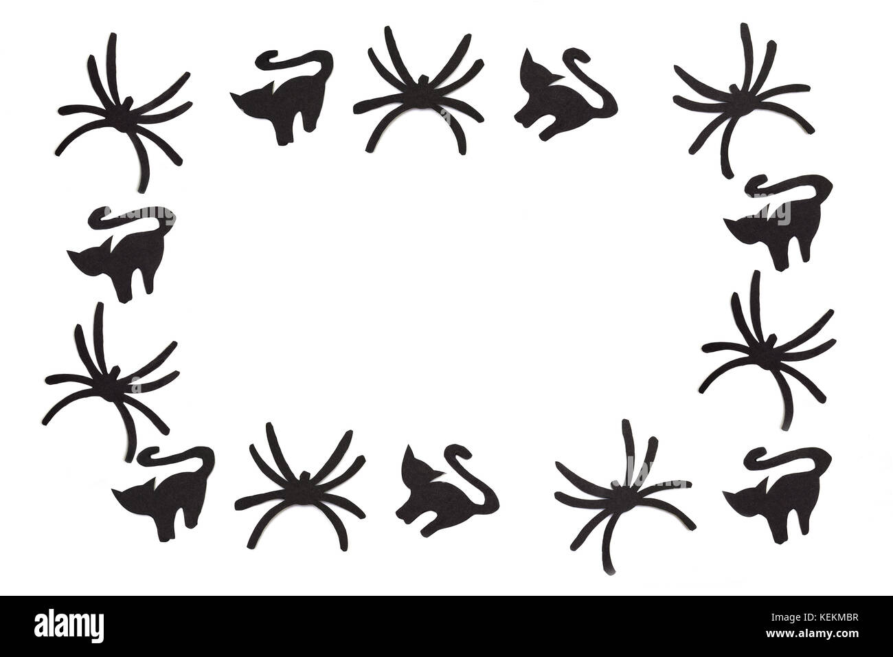 Silhouettes of black cats and spiders carved out of black paper are