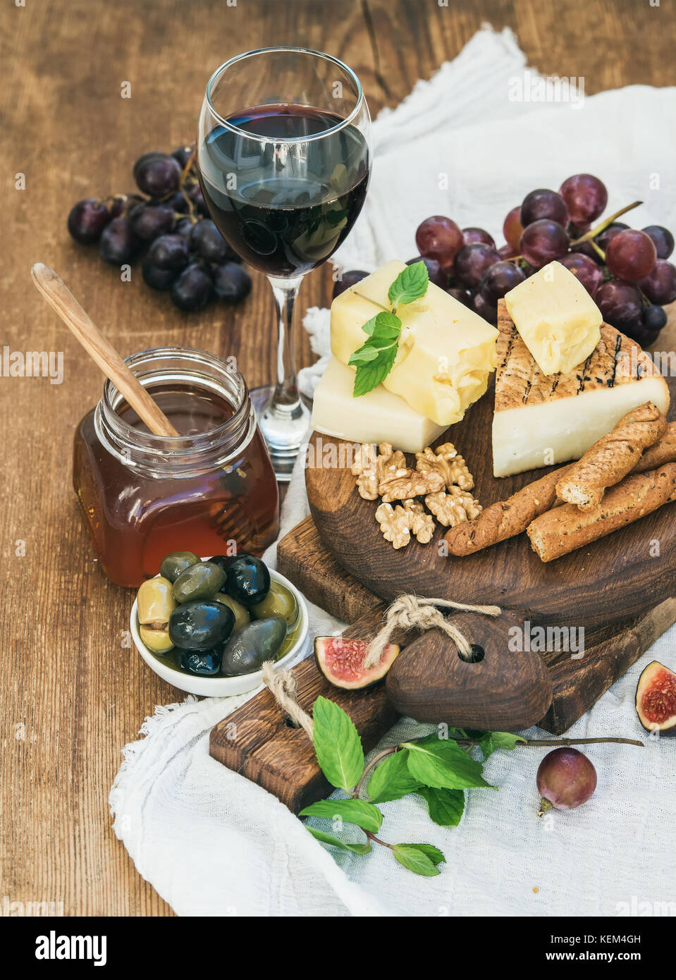 Glass of red wine, cheese board, grapes,fig, strawberries, honey and