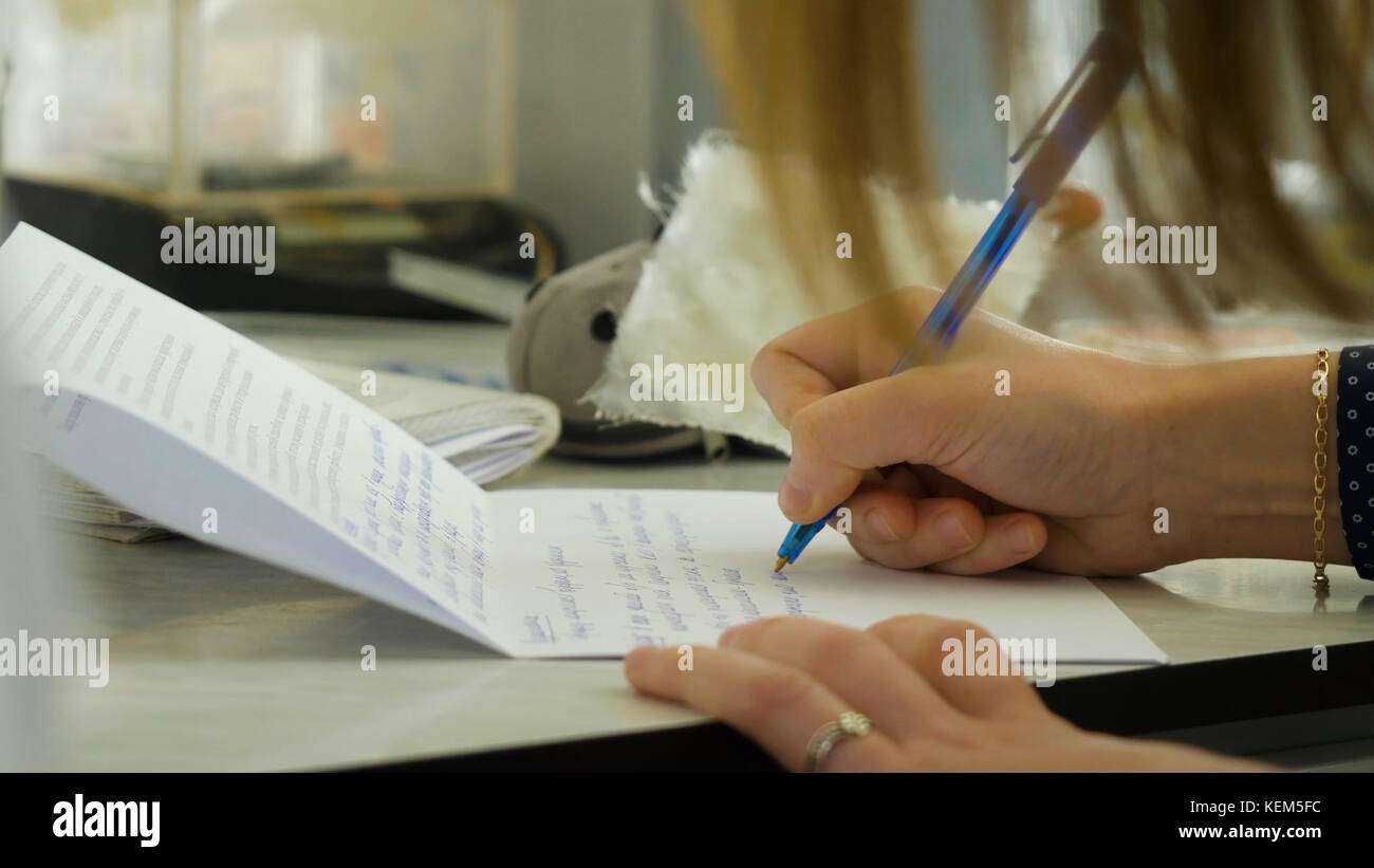 Closeup of a female hand writing on an blank notebook with a pen. Close-up of a female hand writing on an blank notebook with a pen Stock Photo