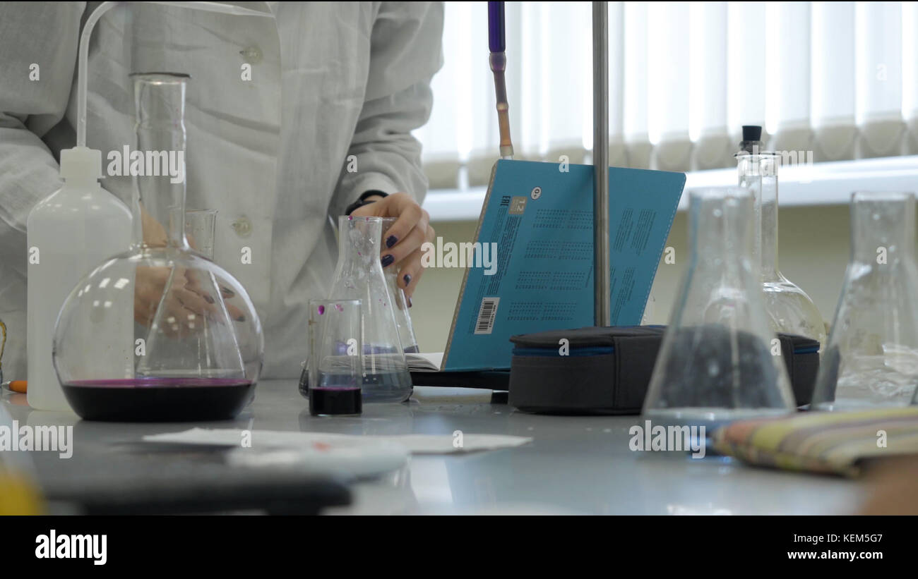 Lab technician doing experiment in lab. Male medical or scientific laboratory researcher performs tests with blue liquid. Scientist working with flasks in laboratory Stock Photo