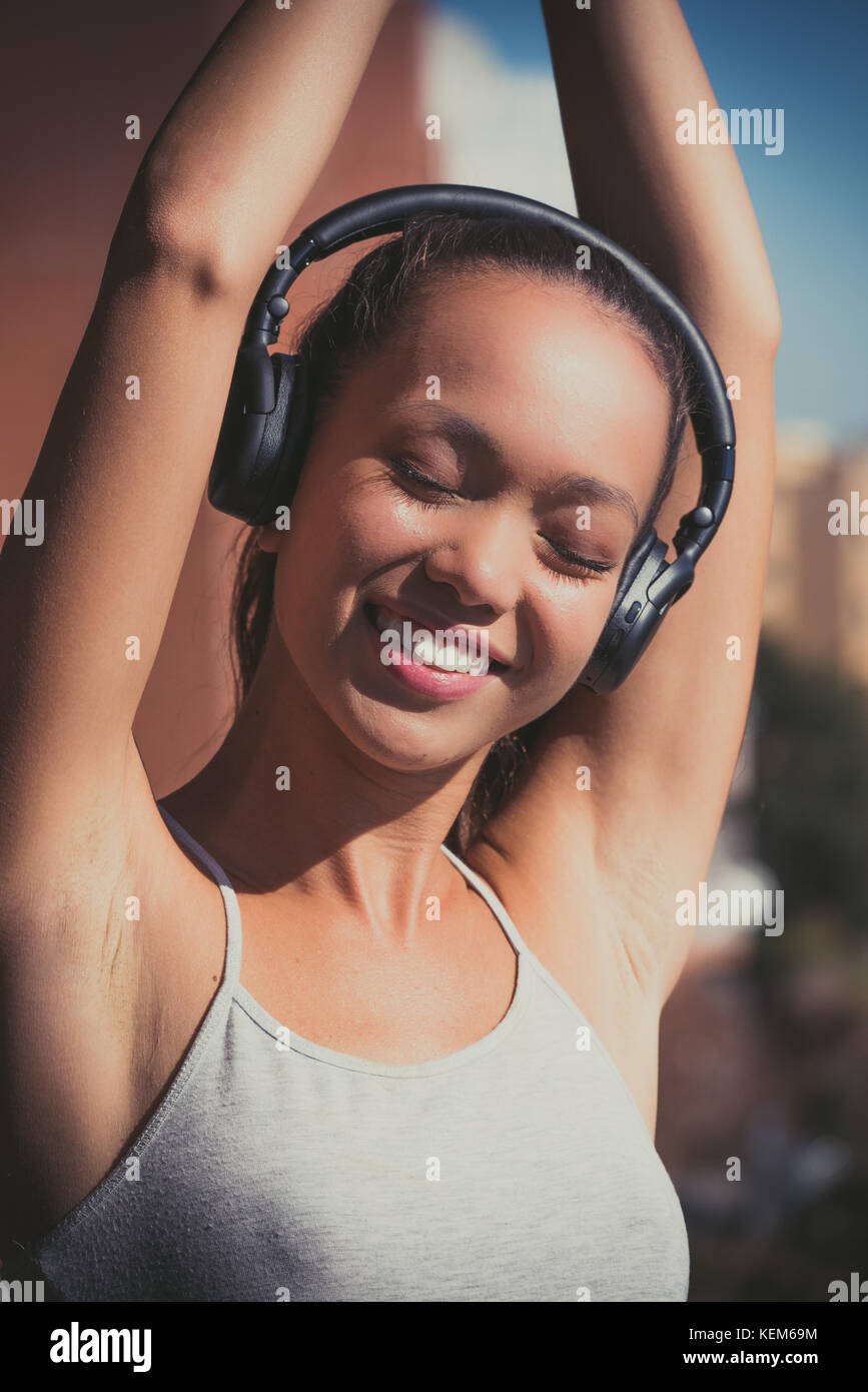 Young asian teen woman outdoor portrait closed eyes sunlight smiling with headphones portrait Stock Photo