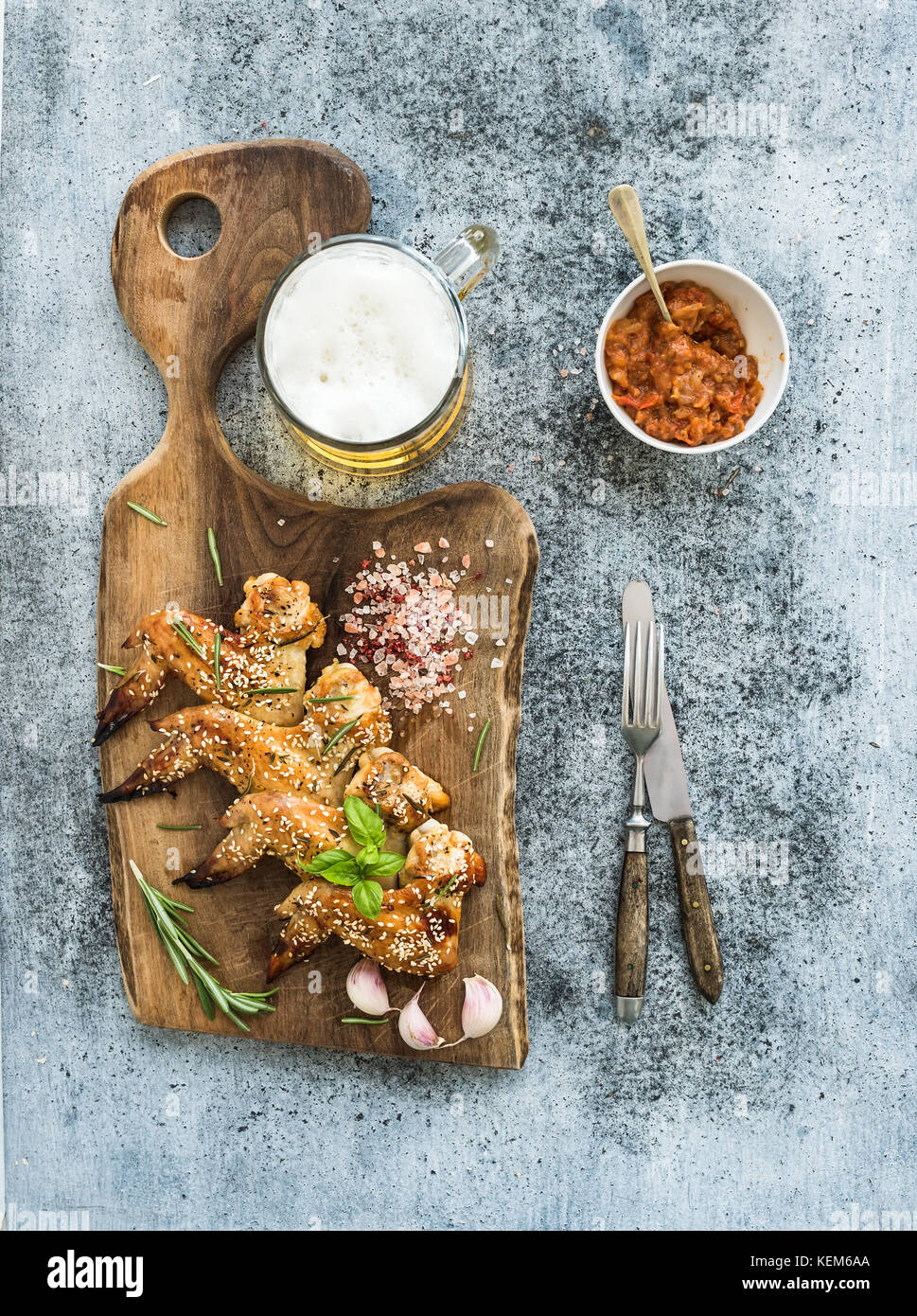 Fried chicken wings on rustic serving board, spicy tomato sauce, herbs