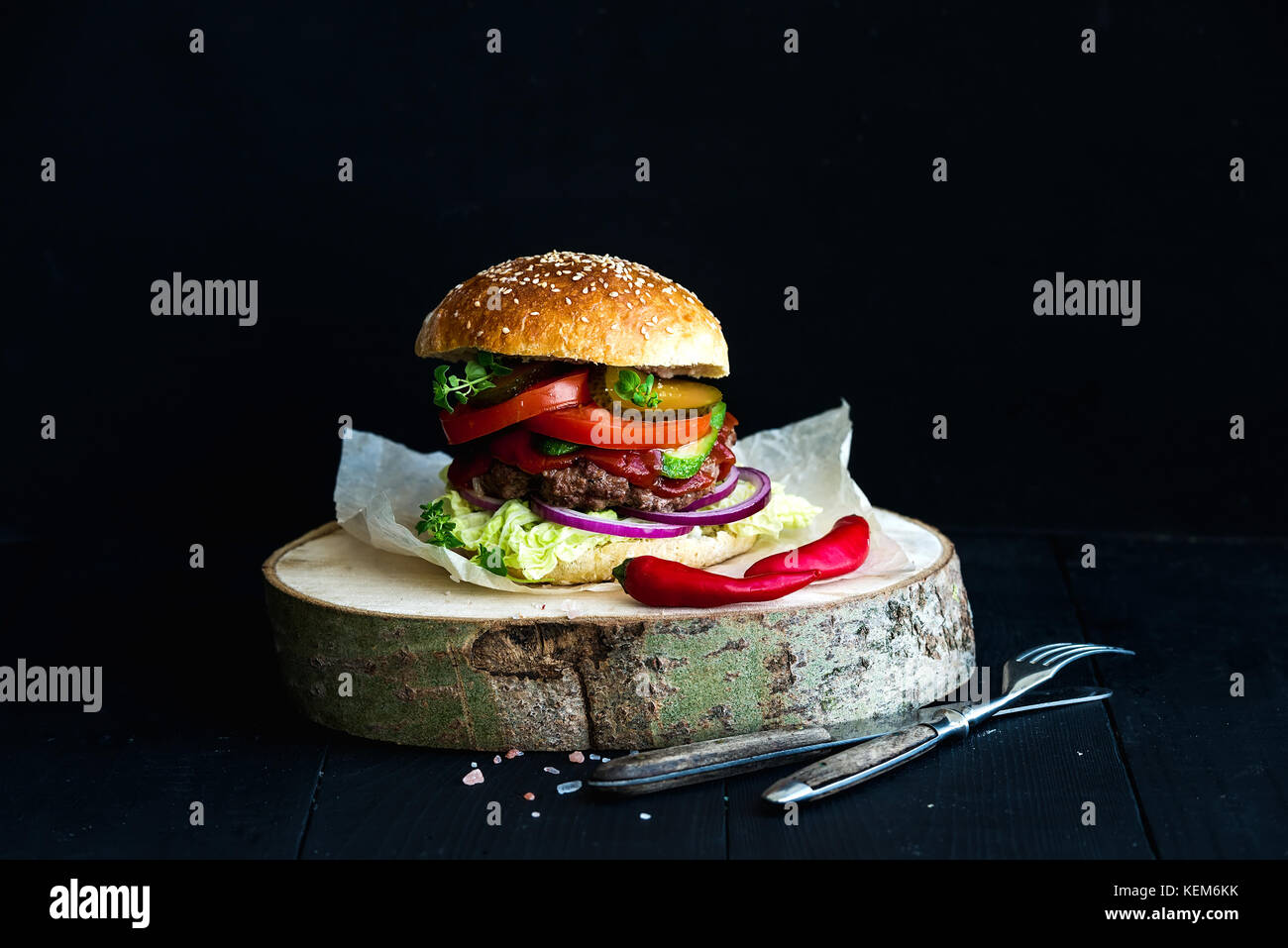 Fresh homemade burger on wooden serving board with spicy tomato sauce