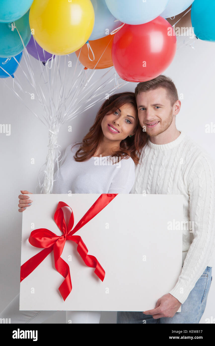 Young smiling couple with balloons and big gift box Stock Photo - Alamy